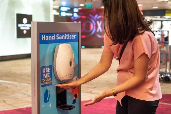 A passenger using the one of the many hand sanitisers at the airport